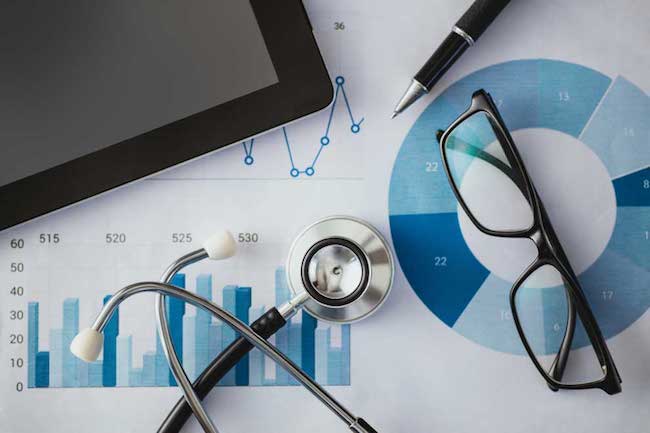 A stethoscope and a pair of glasses on medical charts.