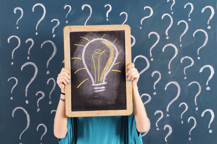 person holding mini chalk board with light bulb drawn on it