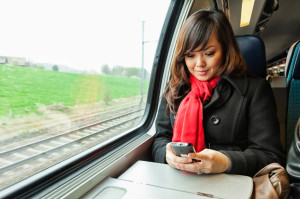 Woman traveling by train holding smartphone