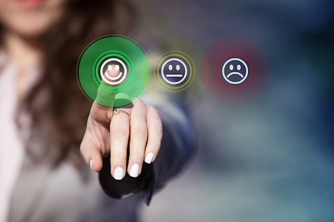 Businesswoman pressing smiley face emoticon on virtual touch screen. Customer satisfaction survey concept.