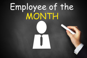 hand writing employee of the month on black chalkboard